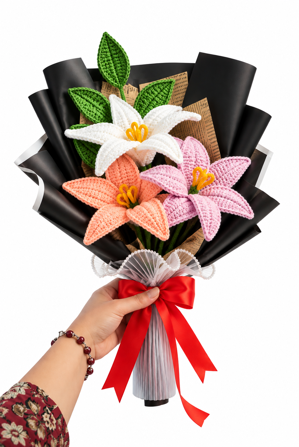 Handcrafted crochet lily bouquet with white, peach and pink flowers, green leaves and a red satin bow