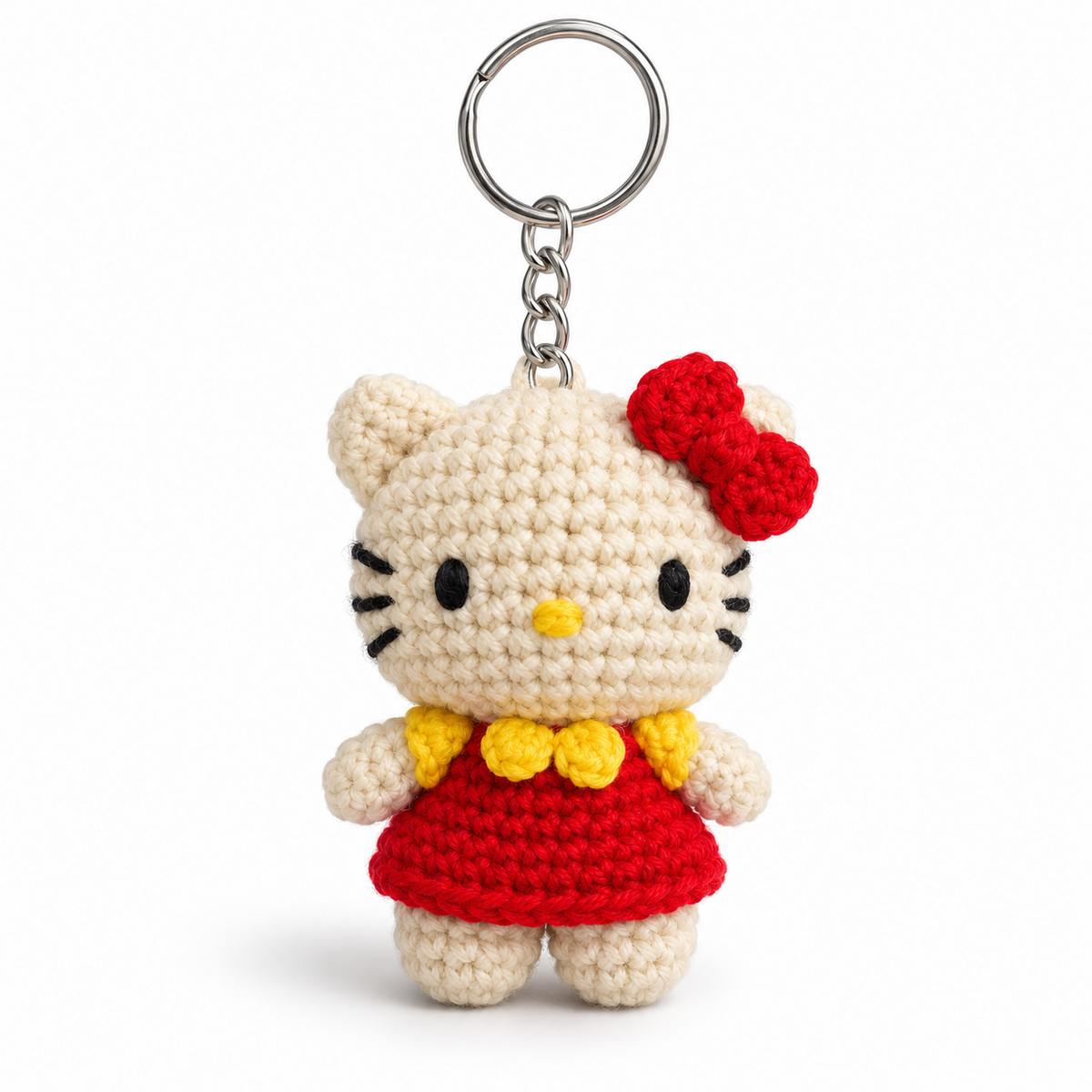 Cream crocheted cat keychain wearing a red dress